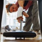 Une femme qui passe l'aspirateur sous la table