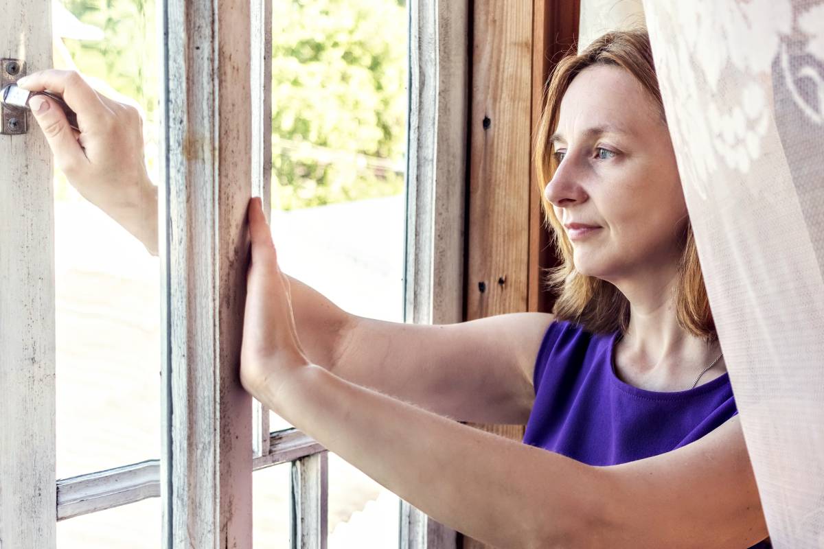 Une femme en train d'ouvrir la fenêtre