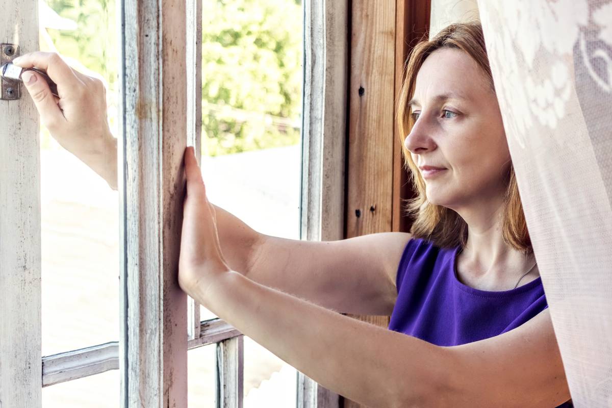 Une femme en train d'ouvrir la fenêtre