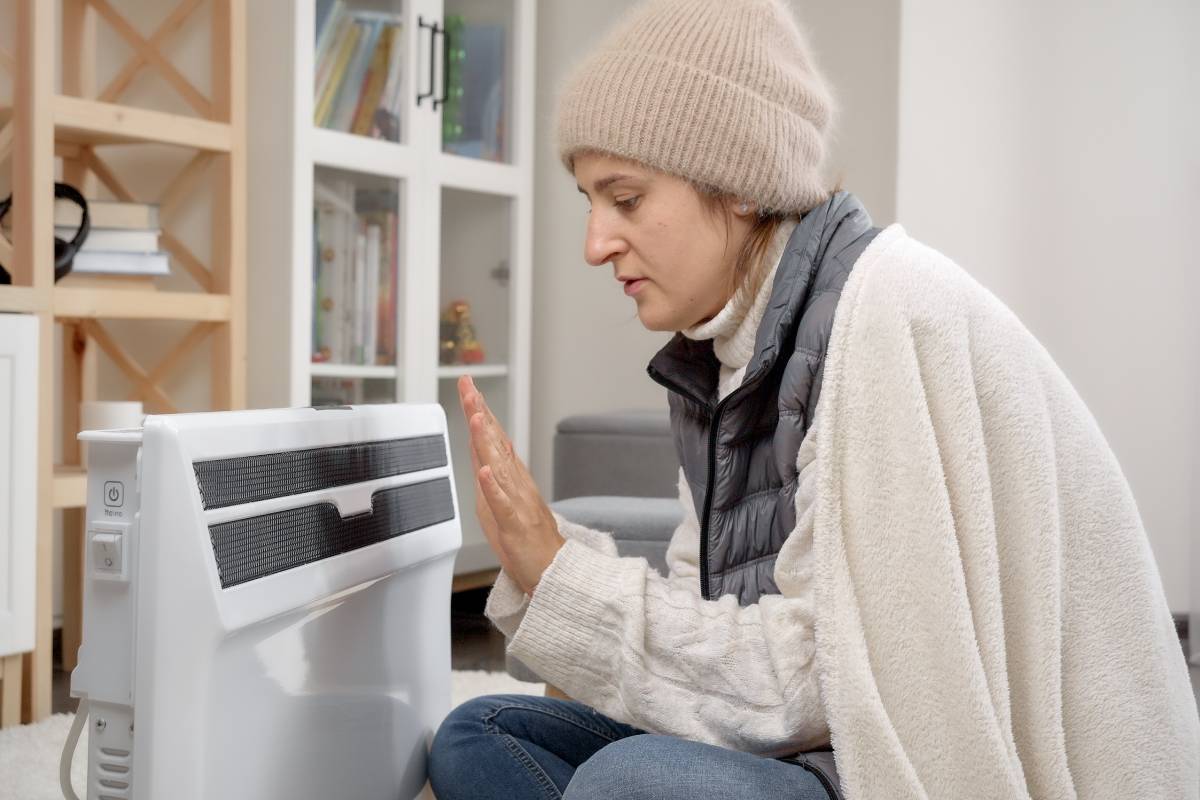 Une femme qui a froid devant son radiateur