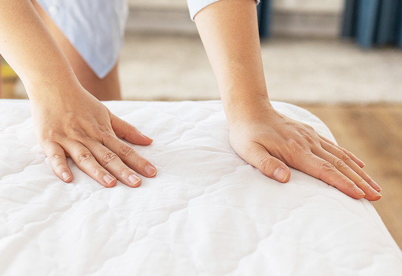 Femme teste la dureté d'un matelas.